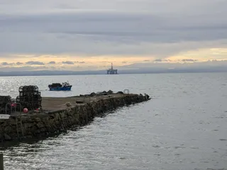 Lobster pots stacked on Lower Largo pier, with a fishing boat moored alongside